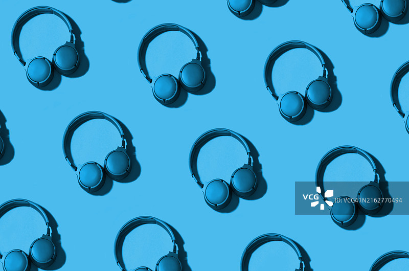 蓝色背景上黑色无线耳机的无缝图案图片素材