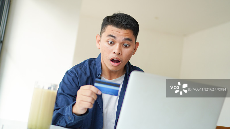 在家用手机信用卡支付账单的年轻男人图片素材