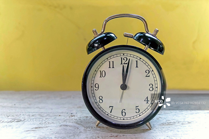 黄色背景的乡村桌子上的黑色闹钟图片素材