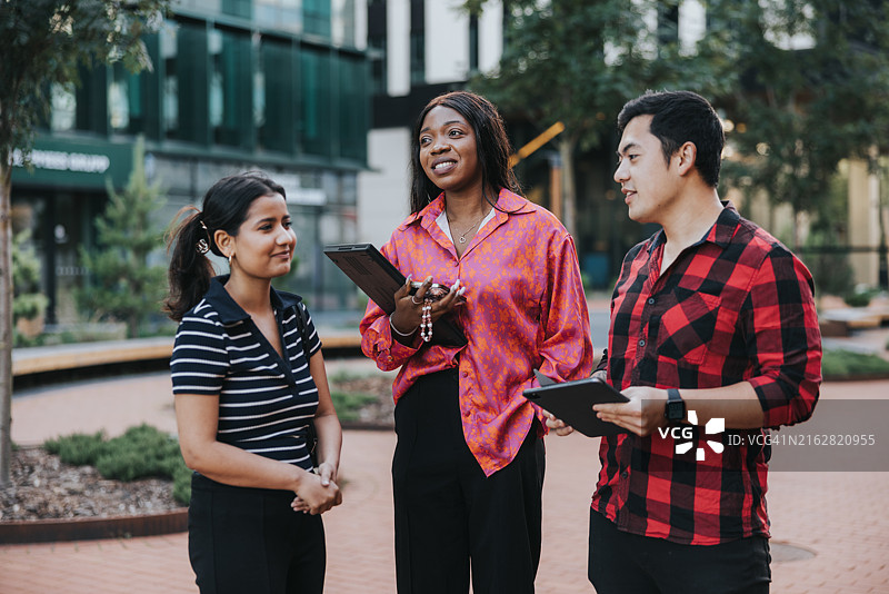 三个年轻的职场人士在上班途中边走边开会图片素材