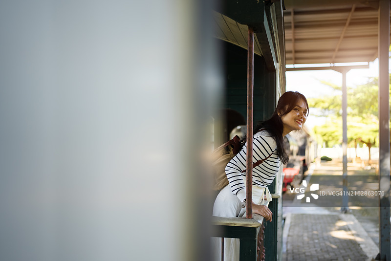 快乐的亚洲女人在车站向朋友挥手图片素材