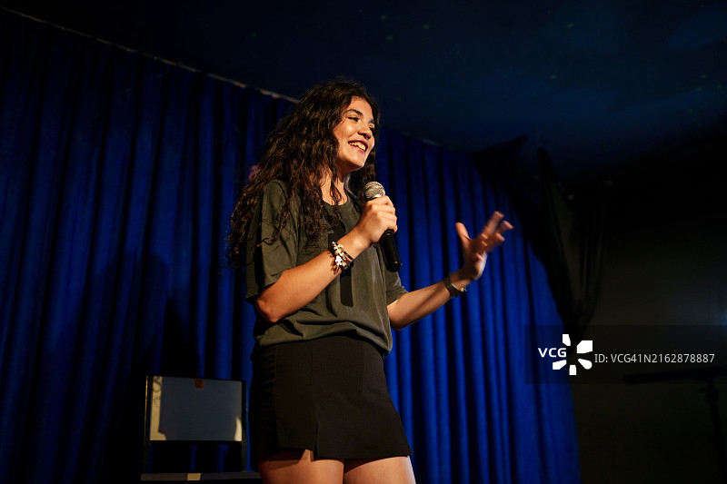 年轻女人在舞台上用麦克风，单口喜剧演员图片素材
