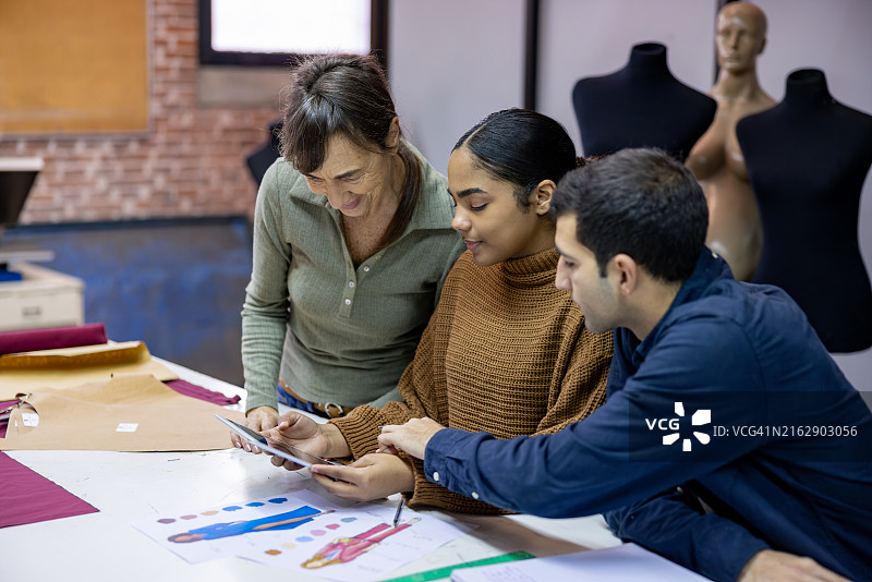 老师在时装设计课上查看学生的设计草图图片素材