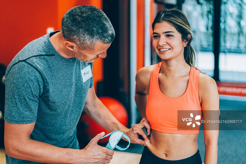 教练用卡尺测量女性身体脂肪图片素材