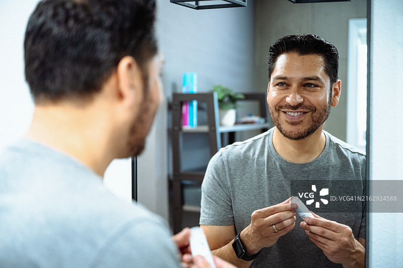 注重面部皮肤护理，涂抹抗衰老乳液的成熟拉丁男人图片素材