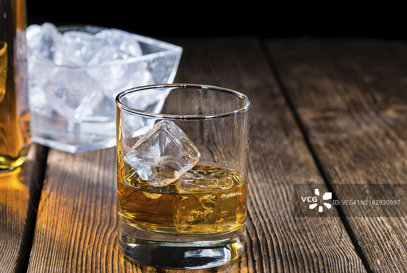 木质背景上的单一麦芽威士忌和冰块图片素材