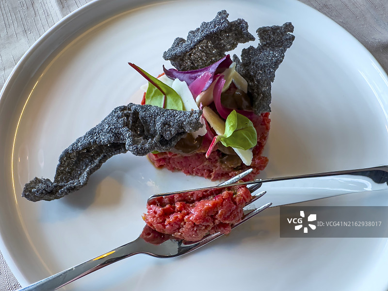 瑞士盘子里的鞑靼牛肉配餐叉和餐刀图片素材