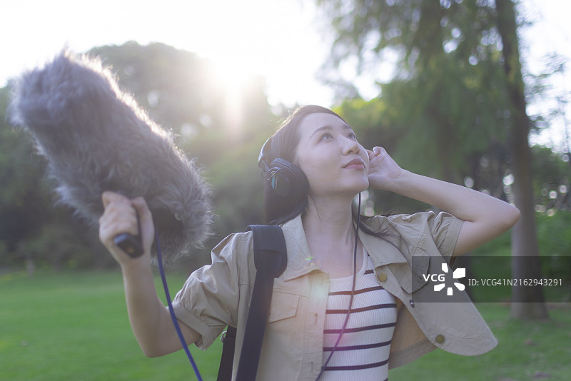 亚洲女性录音师使用枪式麦克风和挡风罩录制自然声音图片素材