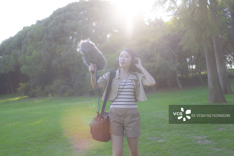 亚洲女性录音师使用枪式麦克风和挡风罩录制自然声音图片素材