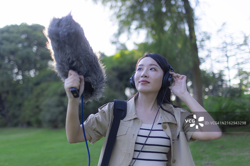 亚洲女性录音师使用枪式麦克风和挡风罩录制自然声音图片素材