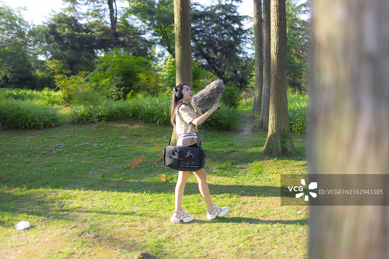亚洲女性录音师使用枪式麦克风和挡风罩录制自然声音图片素材