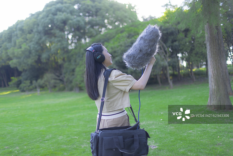亚洲女性录音师使用枪式麦克风和挡风罩录制自然声音图片素材