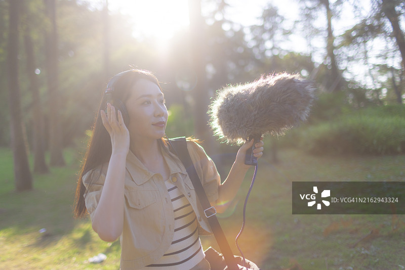 亚洲女性录音师使用枪式麦克风和挡风罩录制自然声音图片素材