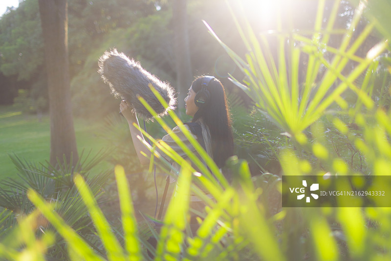 亚洲女性录音师使用枪式麦克风和挡风罩录制自然声音图片素材