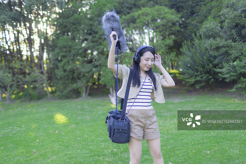 亚洲女性录音师使用枪式麦克风和挡风罩录制自然声音图片素材