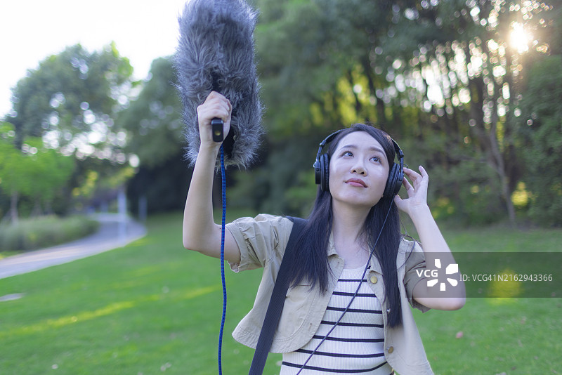 亚洲女性录音师使用枪式麦克风和挡风罩录制自然声音图片素材