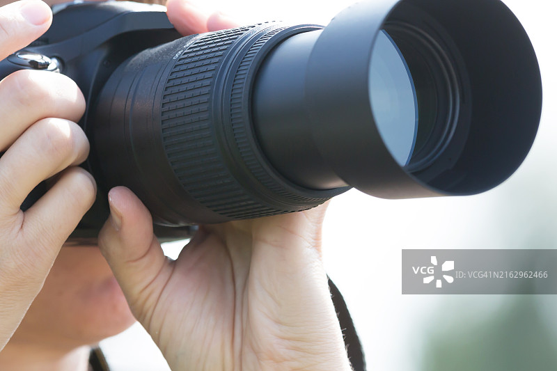 手持带长焦镜头的相机图片素材