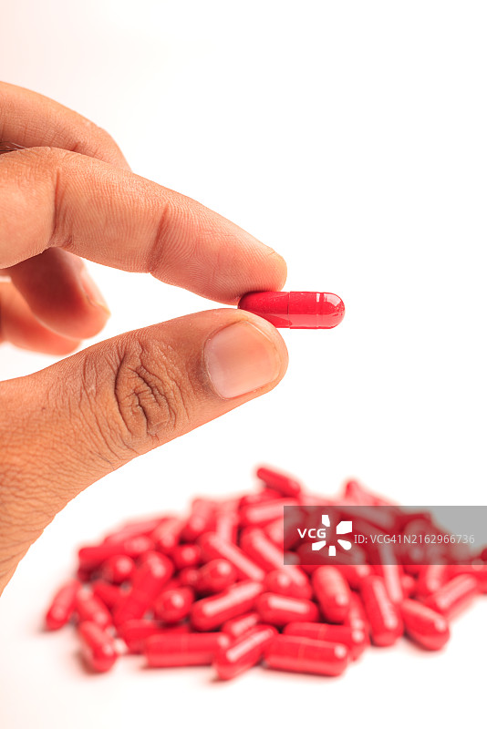 手持红色胶囊药丸图片素材