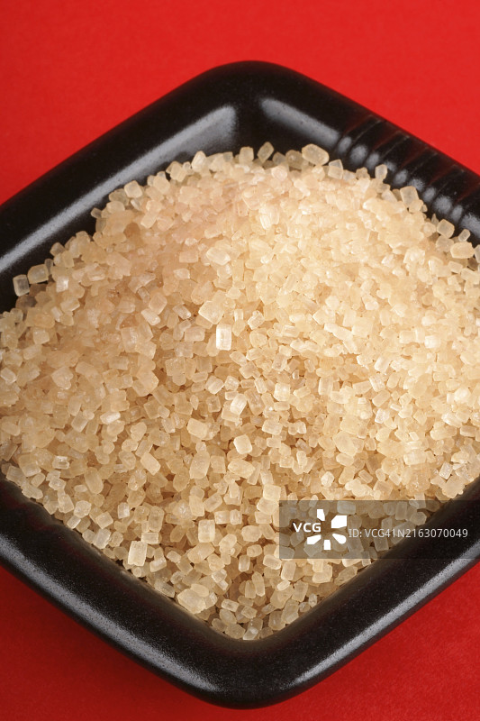 红背景上的黑碗里的红糖图片素材