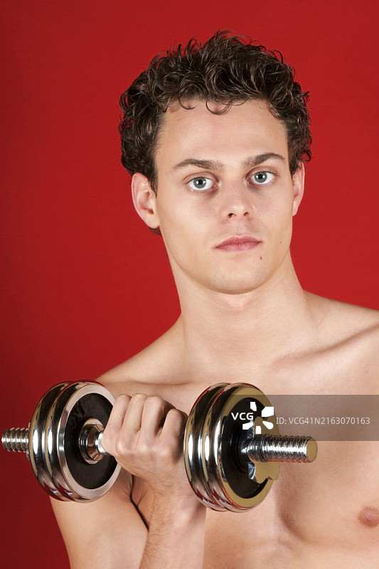 赤膊白人青年用铬哑铃训练图片素材