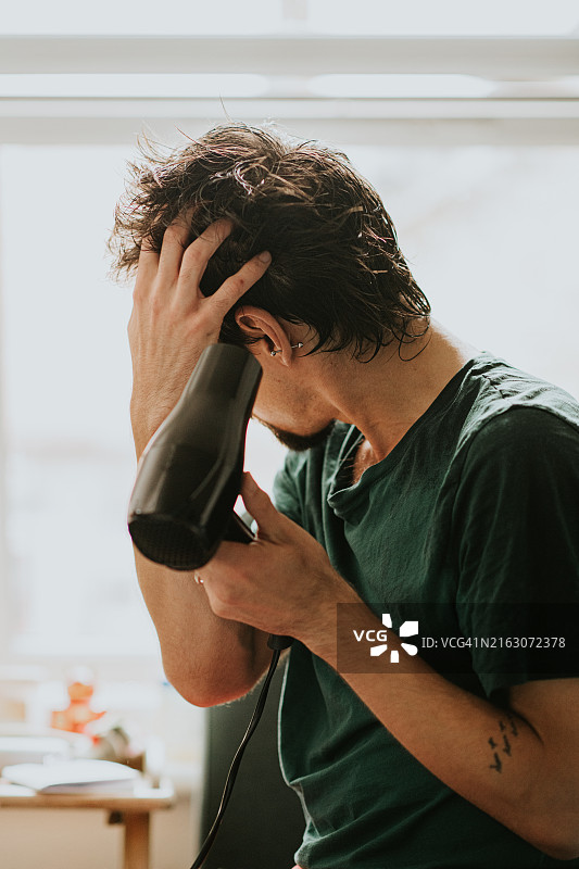 男人用吹风机吹干头发图片素材