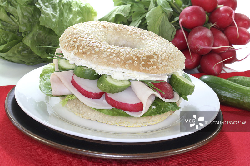 火鸡胸肉、韭菜、萝卜、黄瓜、奶油奶酪和生菜贝果，白色背景图片素材