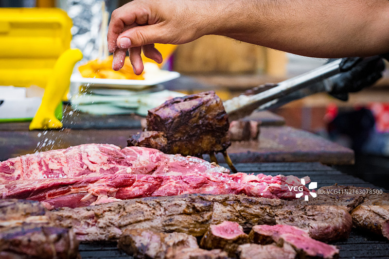 男人在烤架上给肉调味图片素材