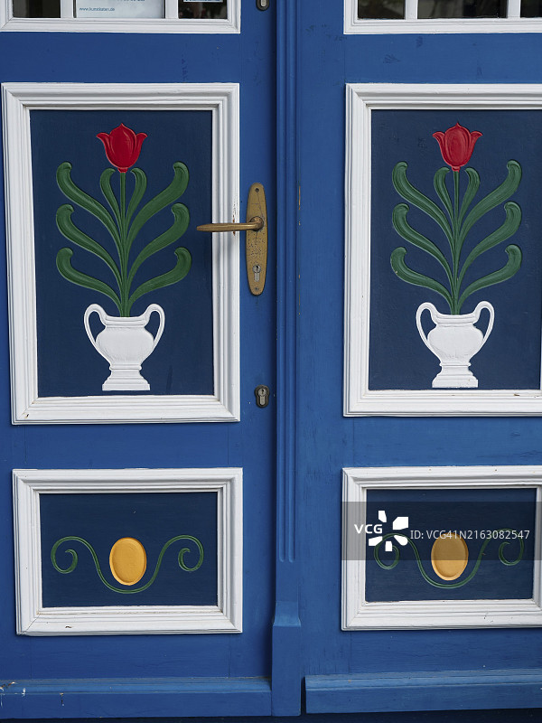 德国阿伦斯霍普，津斯特，蓝色和白色装饰的郁金香图案门与金色门把手特写图片素材