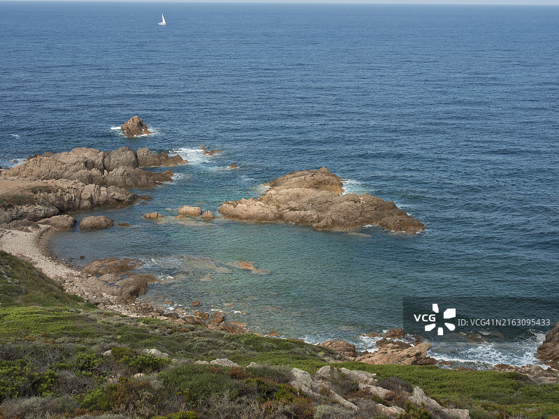 法国科西嘉岛阿雅克肖沿海，清澈的蓝色海水拍打着岩石，天空广阔图片素材
