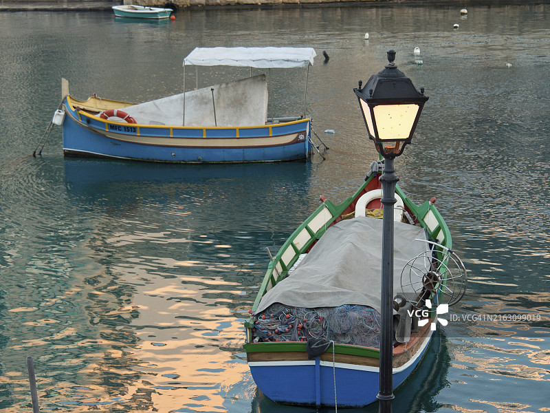 马耳他马尔萨什洛克港，平静水面上漂浮的两艘彩色渔船图片素材