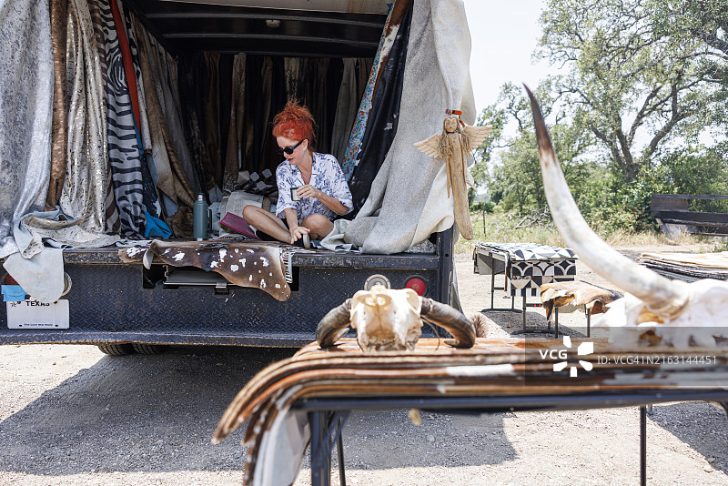 等待顾客：德克萨斯工匠展示乡村风格的牛皮，休息并喝水。中年商人展示西南动物皮图片素材