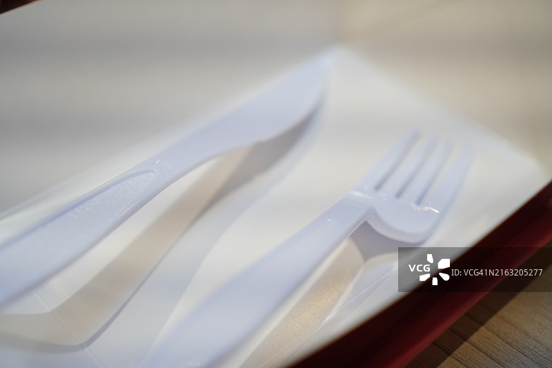白色盘子上的塑料勺子和叉子图片素材