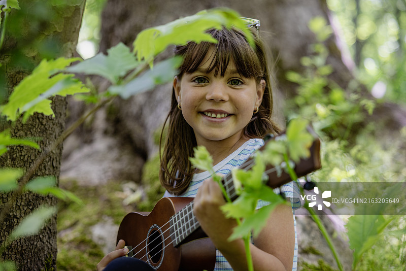 弹着尤克里里的漂亮年轻女孩图片素材