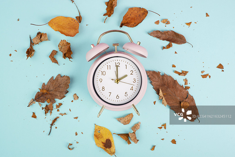 带有秋叶的闹钟，夏令时结束，秋冬季时间转换图片素材