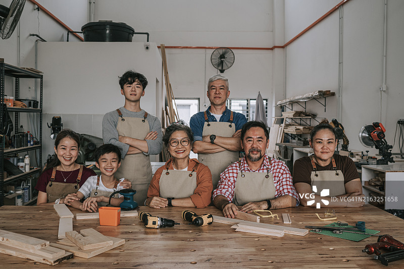亚洲木工车间导师与学生合影，看着镜头微笑图片素材