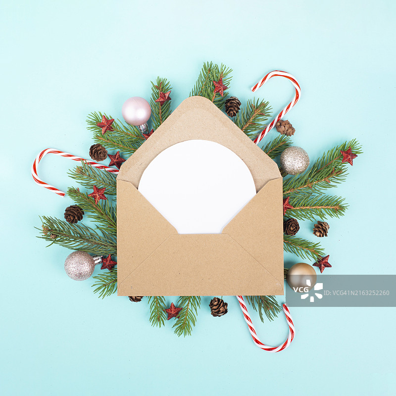 圣诞节假日背景：信封与冷杉树枝、小饰品、糖果手杖和球果冬季贺卡图片素材