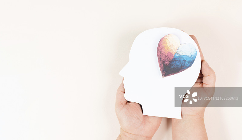 双手捧着带有彩色爱心的头部，象征爱与正能量、慈善与支持图片素材