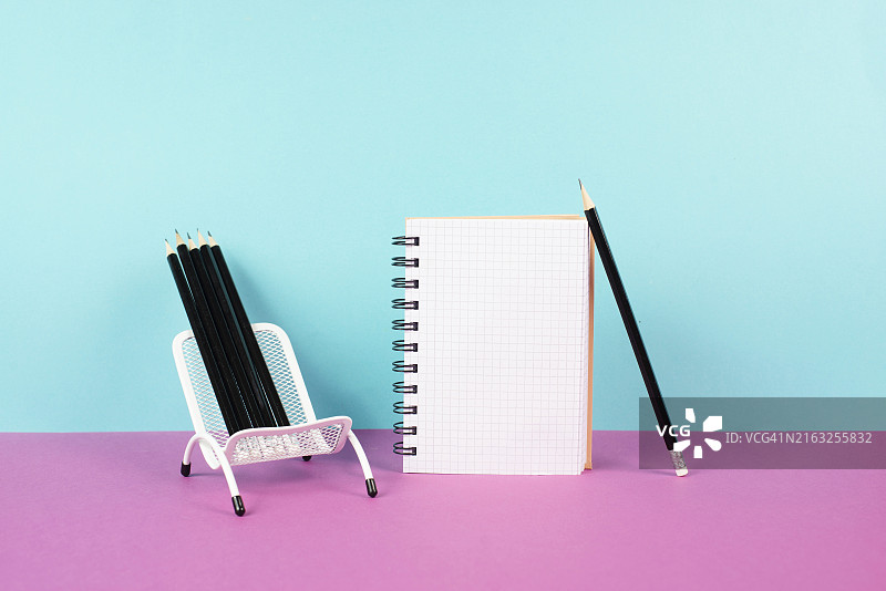 椅子上的空白笔记本和铅笔，激发创意，集思广益，书写信息，粉色和蓝绿色背景图片素材