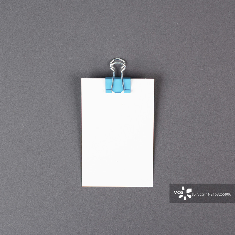 灰色背景上带回形针的空白白纸，文本的复制空间，办公室备忘或消息，沟通概念图片素材