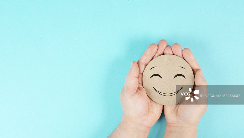 手中拿着笑脸，表达积极情绪和良好客户反馈图片素材