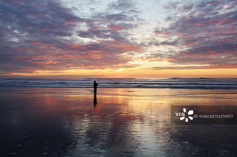 日落时分，男子在海滩钓鱼的剪影，旧金山图片素材