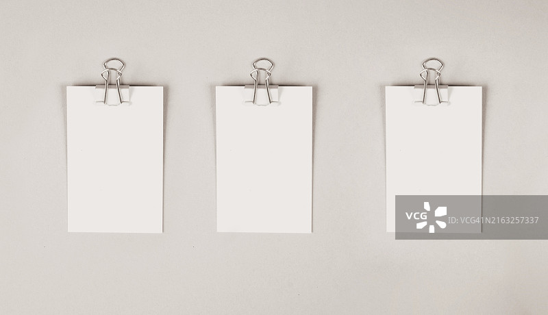 灰色背景上带有曲别针的空白纸，文本的复制空间，办公室备忘录或消息，交流概念图片素材