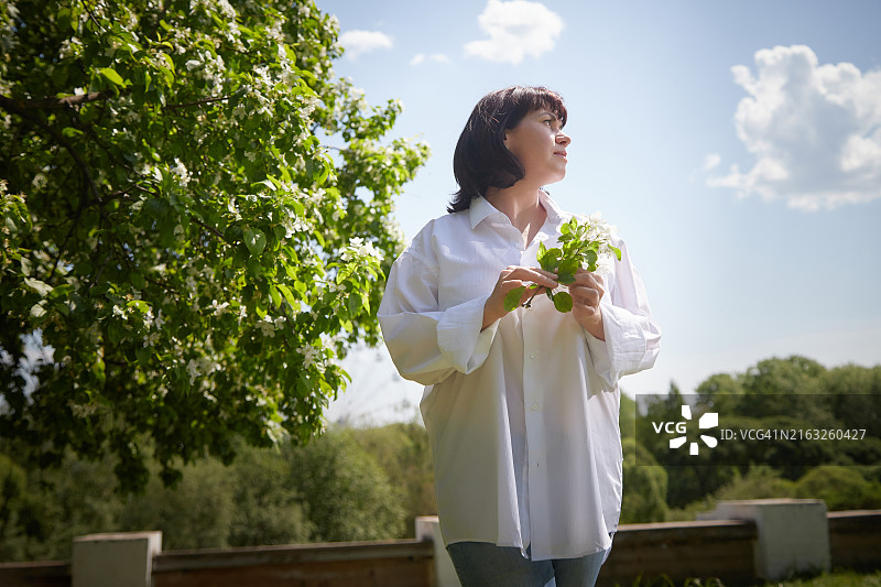 女人在阳光下盛开的苹果树旁散步放松图片素材