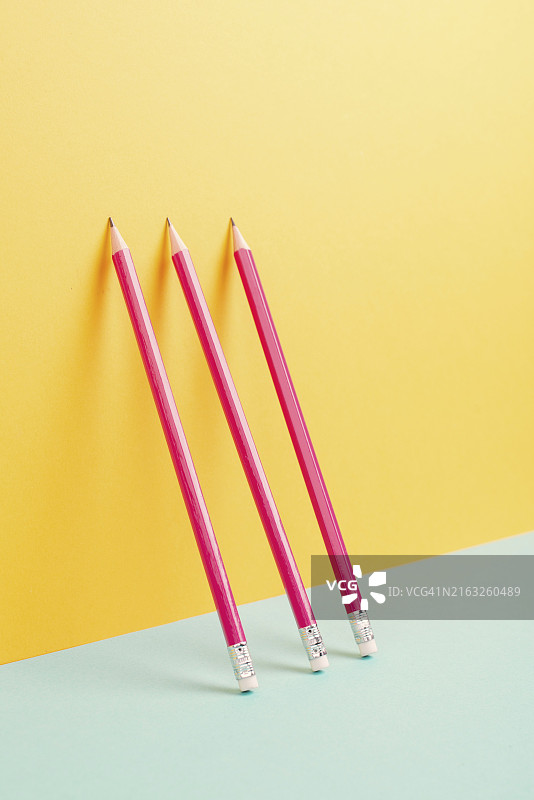 黄色和蓝色背景上的粉色铅笔，极简主义，创意，超现实和教育概念，文本的复制空间，彩色粉色墙图片素材