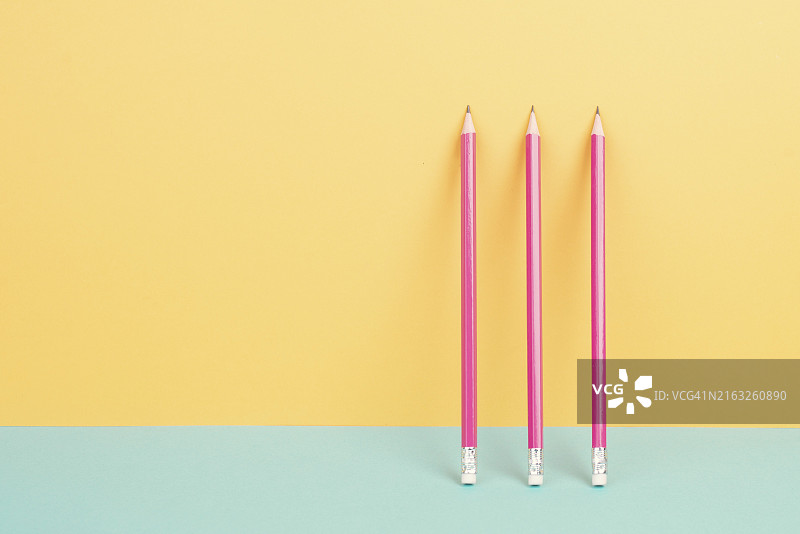 黄色和蓝色背景上的粉色铅笔，极简主义，创意，超现实和教育概念，文本的复制空间，彩色粉色墙图片素材