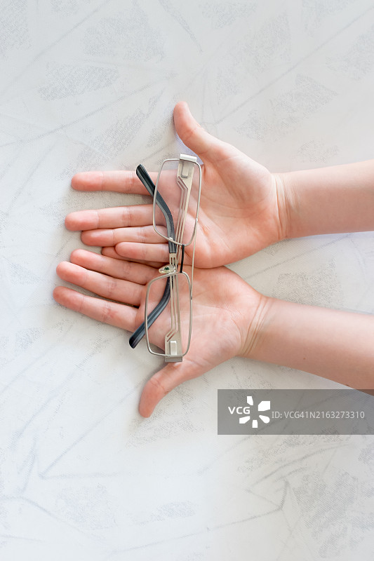 手持眼镜特写，置于桌面图片素材