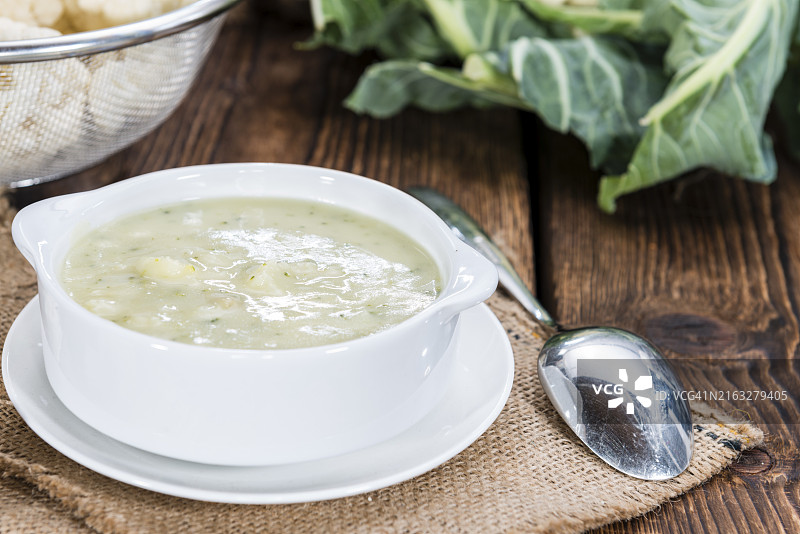 木质背景上的小碗花椰菜汤（特写镜头）图片素材