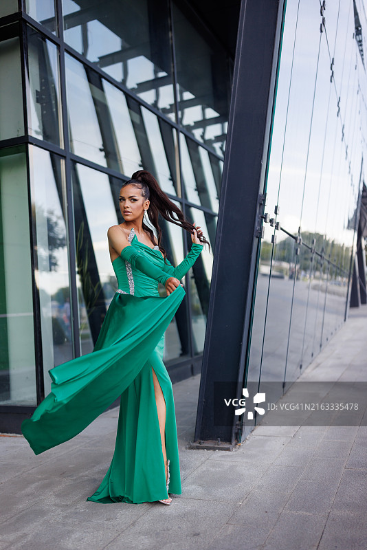 穿着晚礼服在城市里摆姿势的年轻女子图片素材