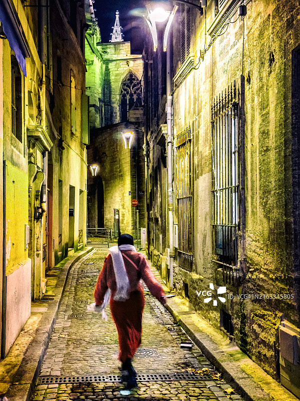 夜晚，单身女子走在狭窄的中世纪小镇街道上的复古风图片图片素材