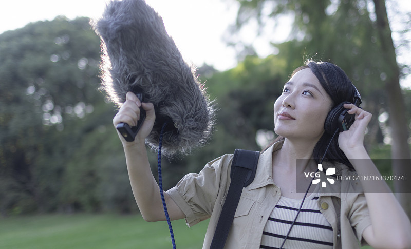 亚洲女性录音师使用枪式麦克风和挡风罩录制自然声音图片素材